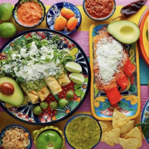 Table full of a variety of foods, sauces, and cheeses.